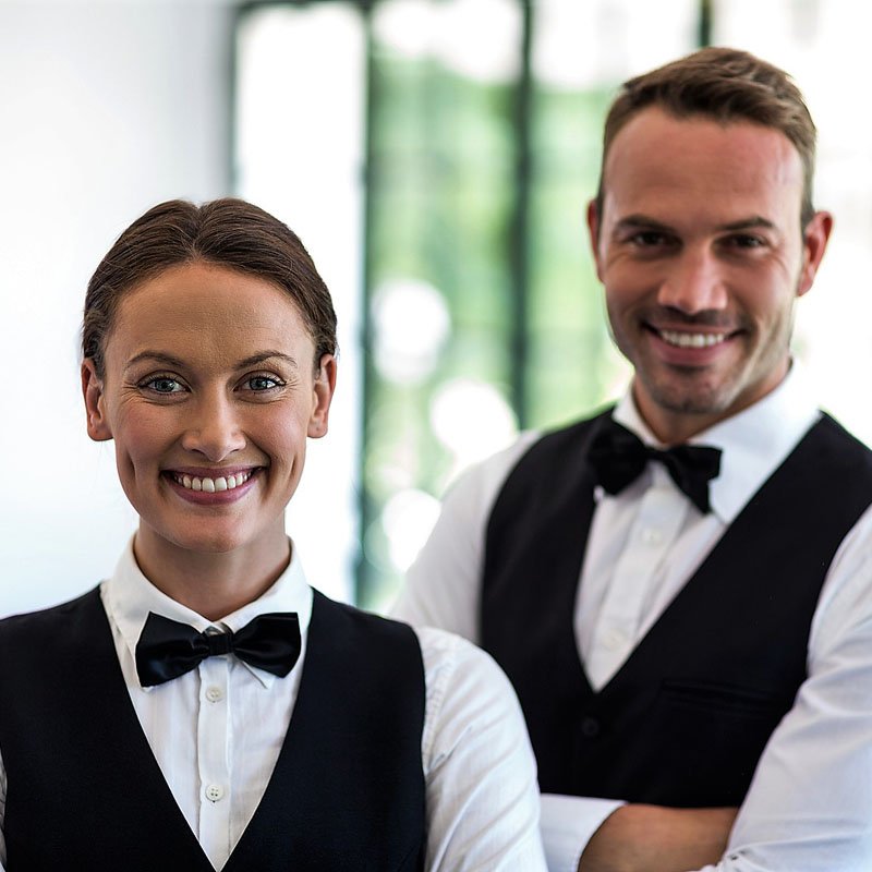 Waiting staff smiling at camera in a commercial kitchen